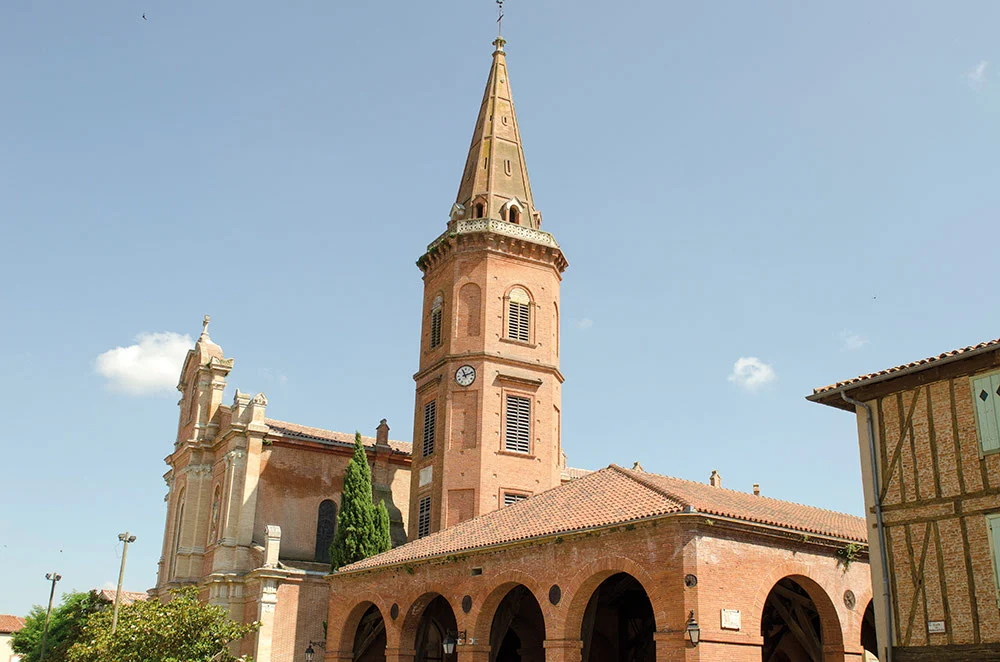 Brick church and arcaded market hall in a village in Occitanie