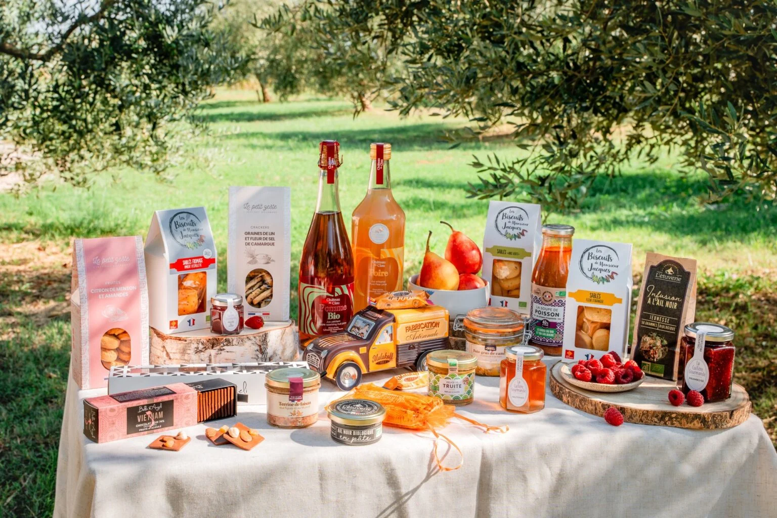 Selection of Occitanie Gourmet producers' products on a table set under olive trees